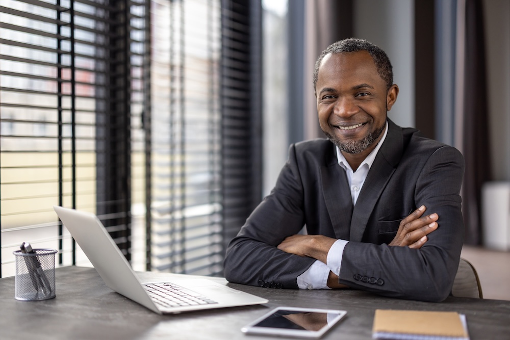 Confident businessman smiling at modern office desk