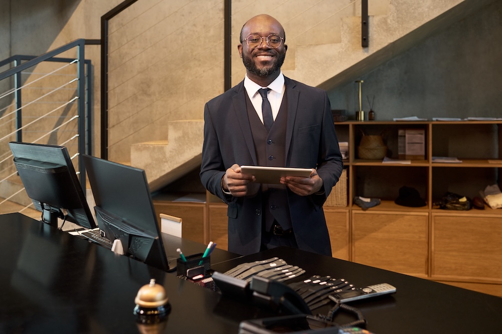 Smiling Businessman Standing in Modern Office Holding Tablet