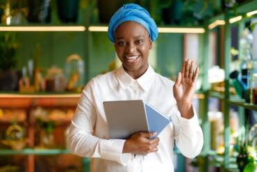 Beautiful african american woman with digital tablet waving at camera